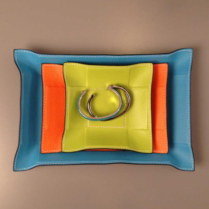 Giobagnara aufeinandergestapelte Lederablagen Jack in unterschiedlichen Größen Formen und Farben - darauf liegen Armreifen Lederablage Jack rechteckig Orange, Größe Medium 15 x 21 cm